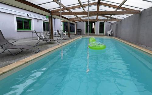 - une piscine avec un jouet vert dans l'eau dans l'établissement Maison spacieuse avec piscine chauffée, à Souillé