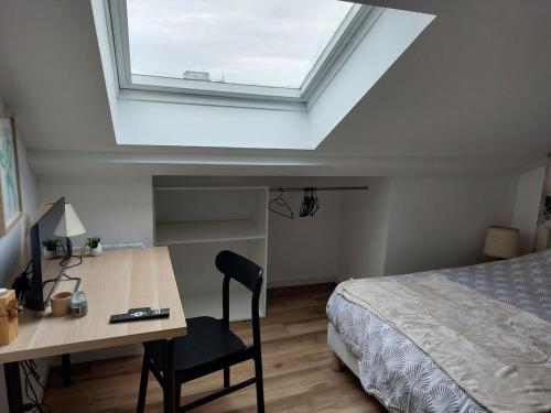- une chambre avec un lit et un bureau avec une lucarne dans l'établissement Sous les toits - Wi-Fi - TV, à Dijon