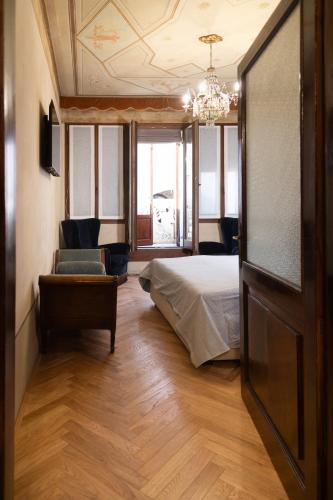 a bedroom with a bed and a couch and a chandelier at B&B al Torrione Belluno in Belluno