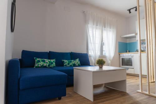 a blue couch in a living room with a table at Estudio completo a estrenar en Triana in Seville