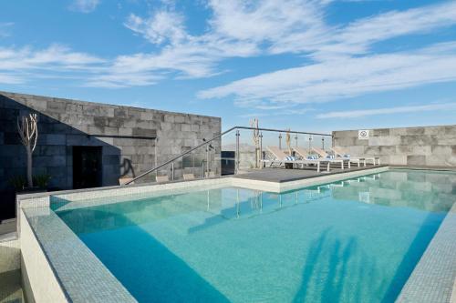 a swimming pool with chairs and a building at Four Points by Sheraton Ciudad Juarez in Ciudad Juárez