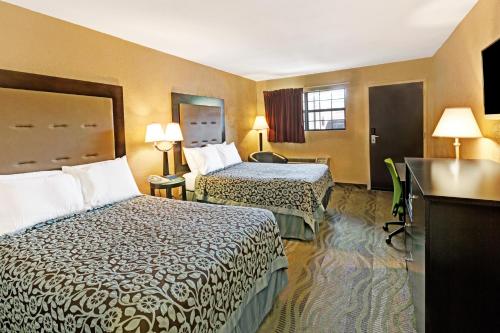 a hotel room with two beds and a television at Days Inn by Wyndham Cherokee Near Casino in Cherokee