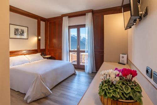 a hotel room with a bed and flowers on a table at Relais Du Foyer in Châtillon