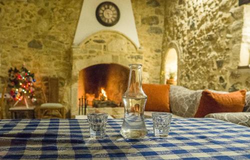 a bottle and two glasses on a table with a fireplace at Hercules Traditional Houses in Gálipe