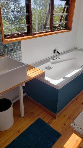 a bath tub sitting under a window next to a sink at Mount 'n Sea Retreat Studio in Victoria Bay