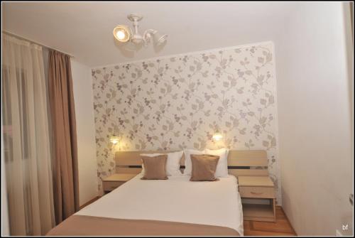 a bedroom with a bed with white sheets and flowers on the wall at Casa Alexa in Sinaia