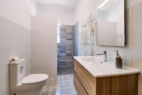 een witte badkamer met een toilet en een wastafel bij Do Jardim in Carvoeiro