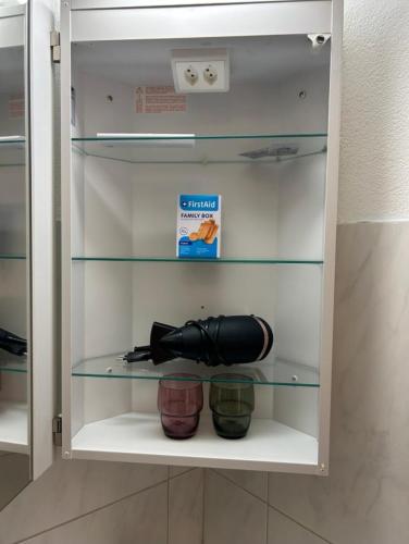 a cupboard with a flashlight and two bowls in it at Comodo appartamento nel cuore dell'Engadina in Celerina