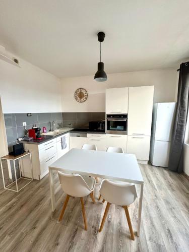 - une cuisine avec une table et des chaises blanches dans l'établissement Panorama, à Bellegarde-sur-Valserine