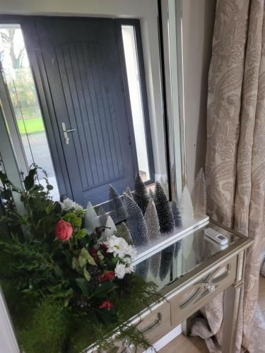a glass table with a bouquet of flowers in front of a door at Beech lodge in Wexford