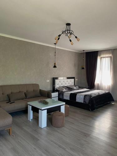 a bedroom with a bed and a couch and a table at Your Cottage in Borjomi