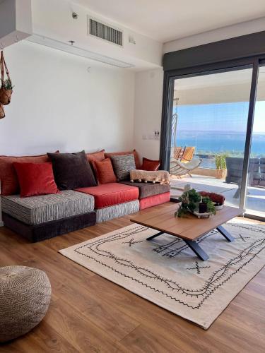 a living room with a red couch and a table at הדירה- C Lake, סי כנרת in Migdal