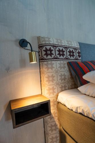a room with a bed and a nightstand with a lamp at ONGA Boutique Lodge in Alta