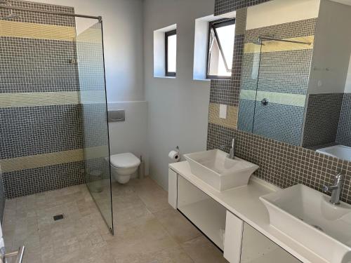 a bathroom with two sinks and a glass shower at Blouberg Village Place in Cape Town