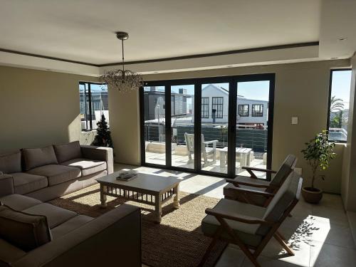 a living room with a couch and chairs and a table at Blouberg Village Place in Cape Town
