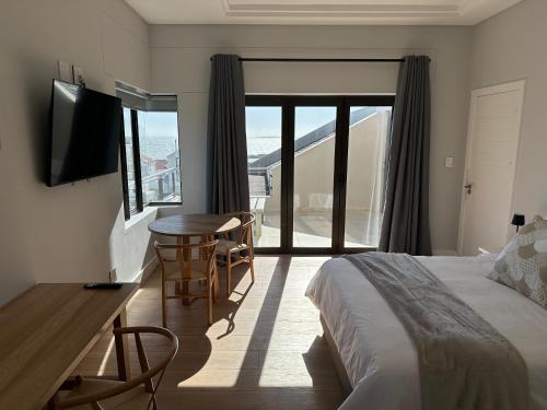 a hotel room with a bed and a table and a window at Blouberg Village Place in Cape Town