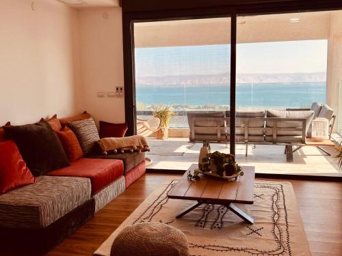 a living room with a couch and a view of the ocean at הדירה- C Lake, סי כנרת in Migdal