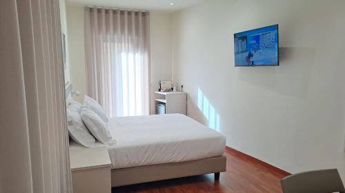 a white bedroom with a bed and a window at Casa al Duomo in Nicosia