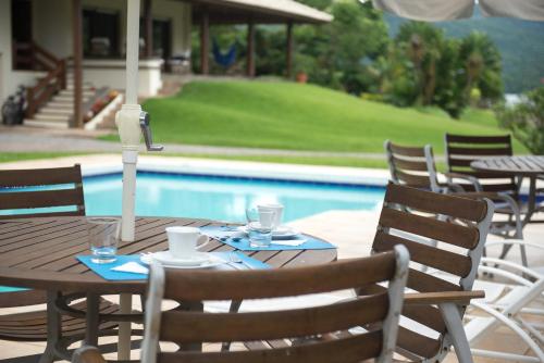 a wooden table and chairs next to a pool at Haute Haus - Guest House in Florianópolis