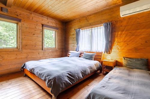 a bedroom with two beds in a wooden cabin at 白馬のスキー場まで４分お洒落なログハウス『白馬 MAMMOTH HOUSE』 in Hakuba