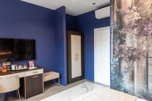 a bedroom with blue walls and a bed and a tv at Adelaide Suite Dreams in Rome