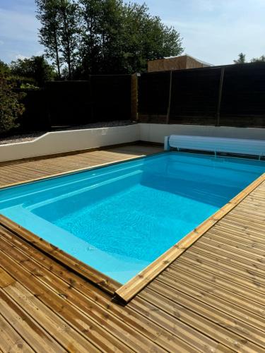 une piscine avec une terrasse en bois et une piscine bleue dans l'établissement La ferme d'Hareauville - Heated swimming pool, à Criquetot-lʼEsneval