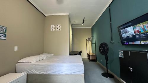 a room with a bed and a flat screen tv at Suíte 09 • Praia das Pitangueiras in Guarujá