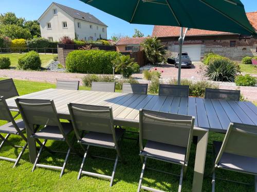 une table en bois avec des chaises et un parasol dans l'établissement La ferme d'Hareauville - Heated swimming pool, à Criquetot-lʼEsneval