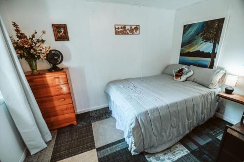 a bedroom with a bed and a wooden dresser and a dresser at Bee-happy rustic cabin in Arkdale