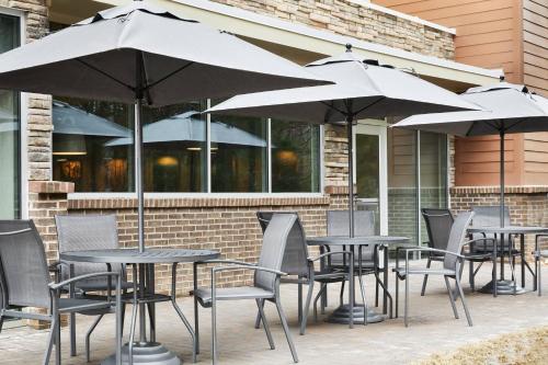 a group of tables and chairs with umbrellas at Fairfield Inn & Suites by Marriott Raleigh Wake Forest in Wake Forest