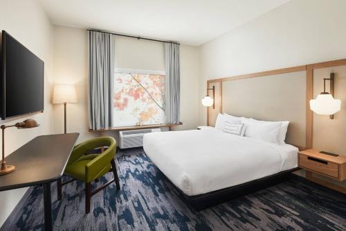 a hotel room with a bed and a desk and a television at Fairfield Inn & Suites by Marriott Raleigh Wake Forest in Wake Forest