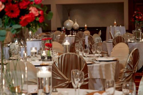 a dining room with white tables and chairs and flowers at Chicago Marriott Northwest in Hoffman Estates