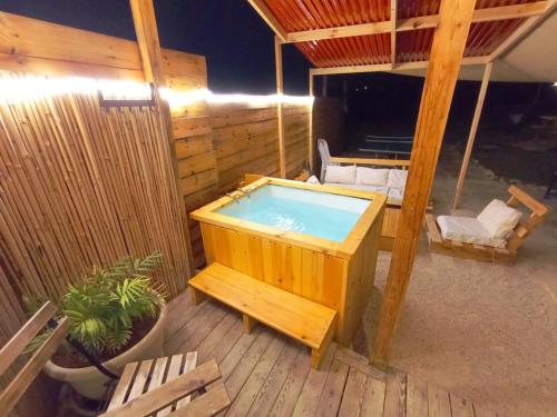 a hot tub sitting on a wooden deck with chairs at Olive Dome - כיפה גיאודזית ענקית ומודרנית בין עצי הזית in Yavneʼel
