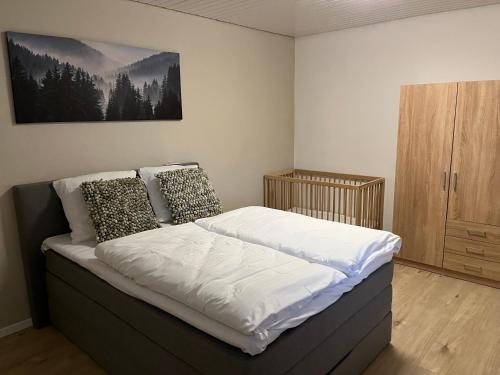 a bedroom with a bed with white sheets and pillows at Ferienwohnung am Waltenberg in Winterberg