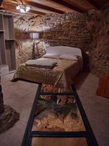 a bedroom with a bed in a stone wall at Il Cortiletto del Borgo in Pietra Montecorvino