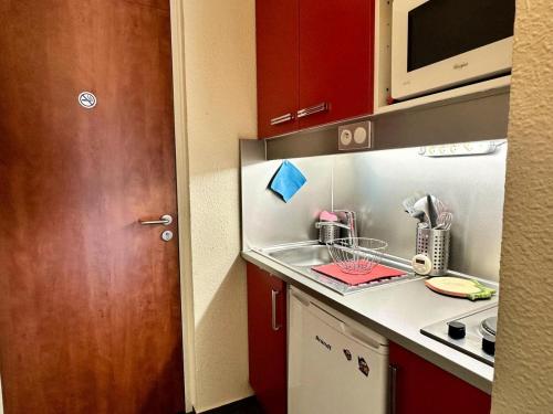 une petite cuisine avec un évier et un micro-ondes dans l'établissement Résidence Le Tourmalet - maeva Home - Studio 5 personnes - Confort MAE-0361, à La Mongie