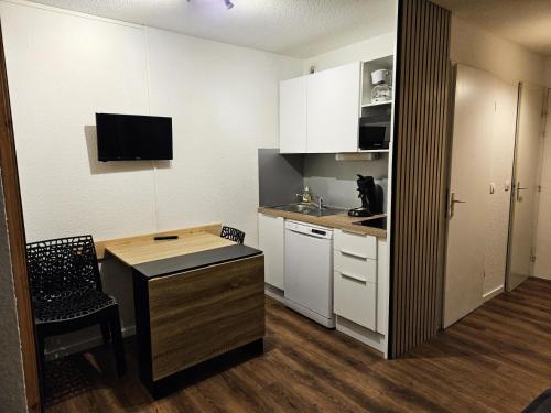 Il comprend une petite cuisine avec un bureau et une table. dans l'établissement Résidence Les Horizons d'Huez - maeva Home - Appartement 2 pièces 4 personnes - Sélection MAE-3871, à Huez