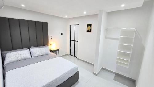 a white bedroom with a bed and a book shelf at Oasis Moods Holiday Homes in Al Ain