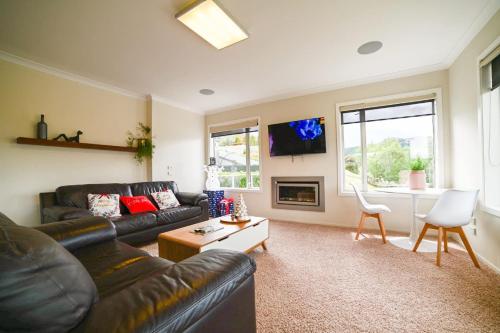 a living room with a leather couch and a table at Ohana Tekapo Vista - 3BR Hot Tub & Stunning Views in Lake Tekapo
