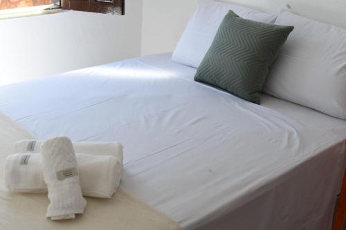 Una cama blanca con una toalla encima. en Casa confortável e aconchegante, en Lençóis