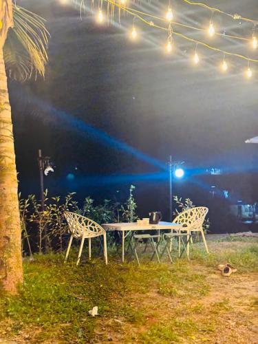 a table with chairs and lights in a field at House Of Munnar in Anachal