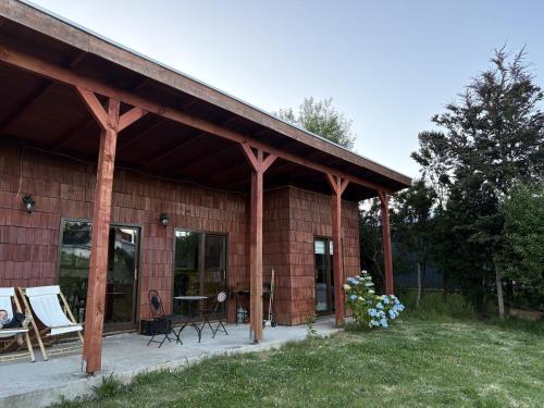 a wooden house with a patio and a table and chairs at Rio Blanco in Hornopiren