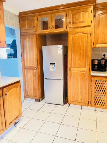 a white refrigerator in a kitchen with wooden cabinets at Emanzini Self-catering guesthouse in Mtwalume