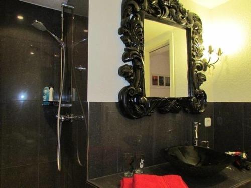 une salle de bain noire avec un lavabo et un miroir dans l'établissement Nordlicht, à Hamburgerdeich