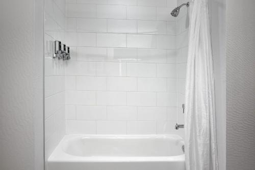 a white bath tub in a white tiled bathroom at Four Points by Sheraton Sherwood Park in Sherwood Park