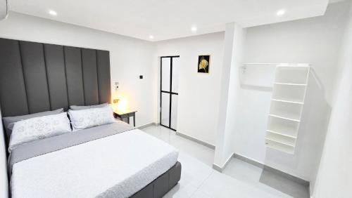 a white bedroom with a bed and a book shelf at Oasis Moods Holiday Homes in Al Ain