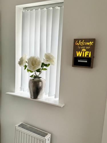 a window with a vase with flowers on a shelf at Harmony House 3 Bedroom New Build for Families, Contractors, Black Country Museum Sleeps 6 in Tipton