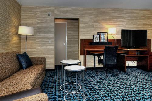 a hotel room with a couch and a desk with a computer at Fairfield Inn & Suites by Marriott Los Angeles Rosemead in Rosemead