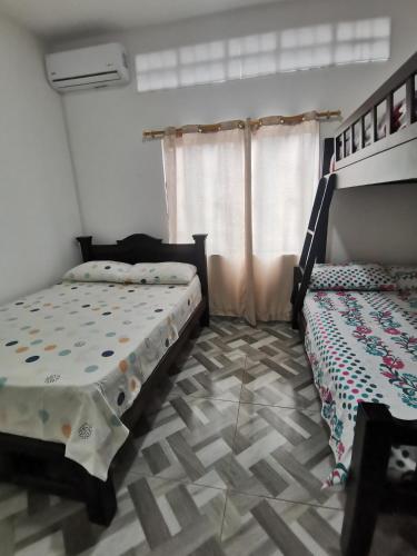 a bedroom with two beds and a tiled floor at Apartamento moderno con AC y WiFi Ideal para grupos in Honda