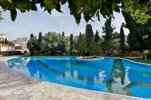 a blue swimming pool with trees in the background at Stunning & Cosy, Direct Pool Access, 2BR, with Private Patio! Serenity Townhouse in Paphos